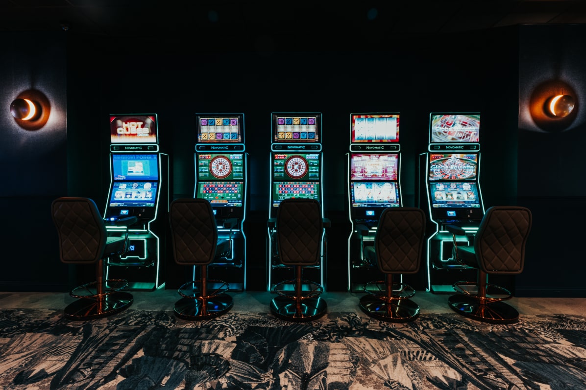 Rangée de machines à sous scintillantes au Casino Elite Quiévrain, invitant à l'aventure du jeu.
